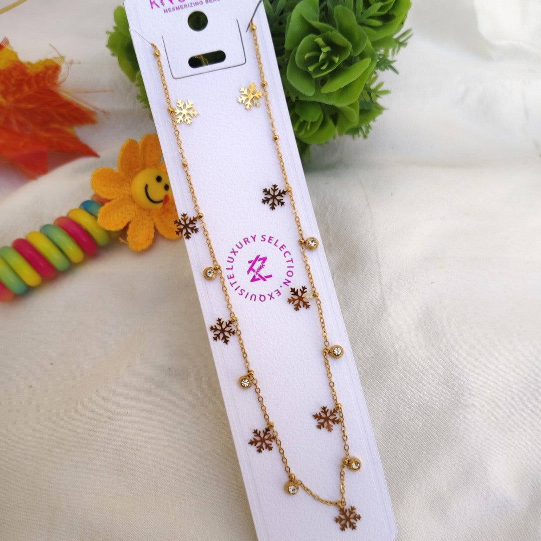 Necklace with floral designs on a white card with brand logo, surrounded by decorative items.