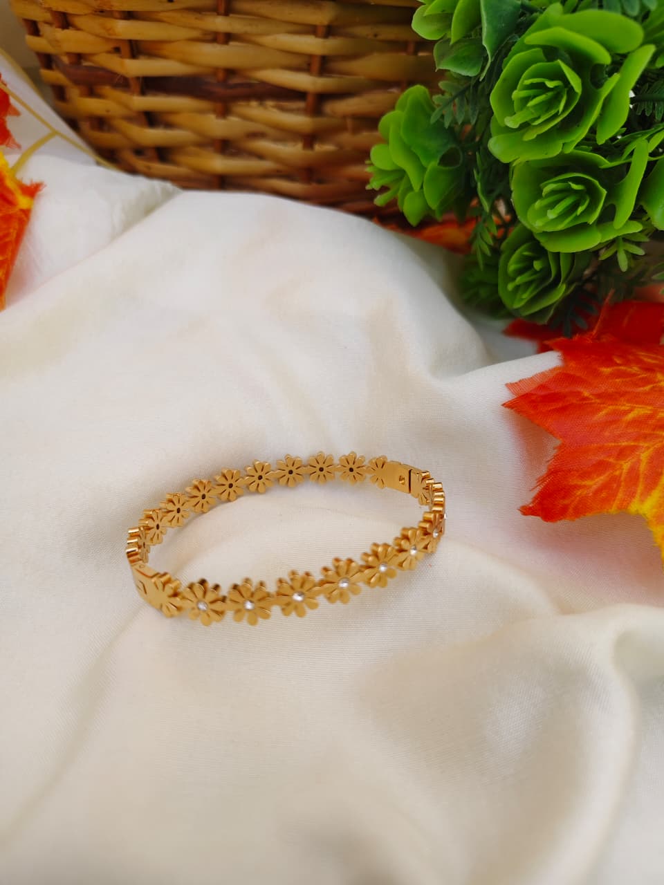 Detailed gold-tone flower charm bracelet on a delicate chain, feminine botanical jewelry style.