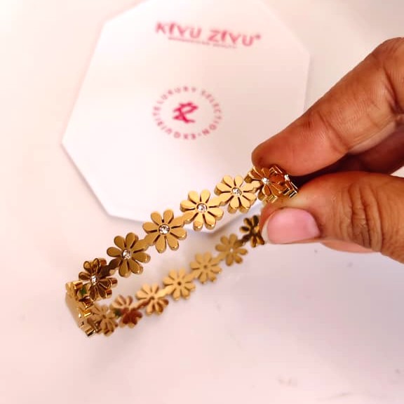 Detailed gold-tone flower charm bracelet on a delicate chain, feminine botanical jewelry style.
